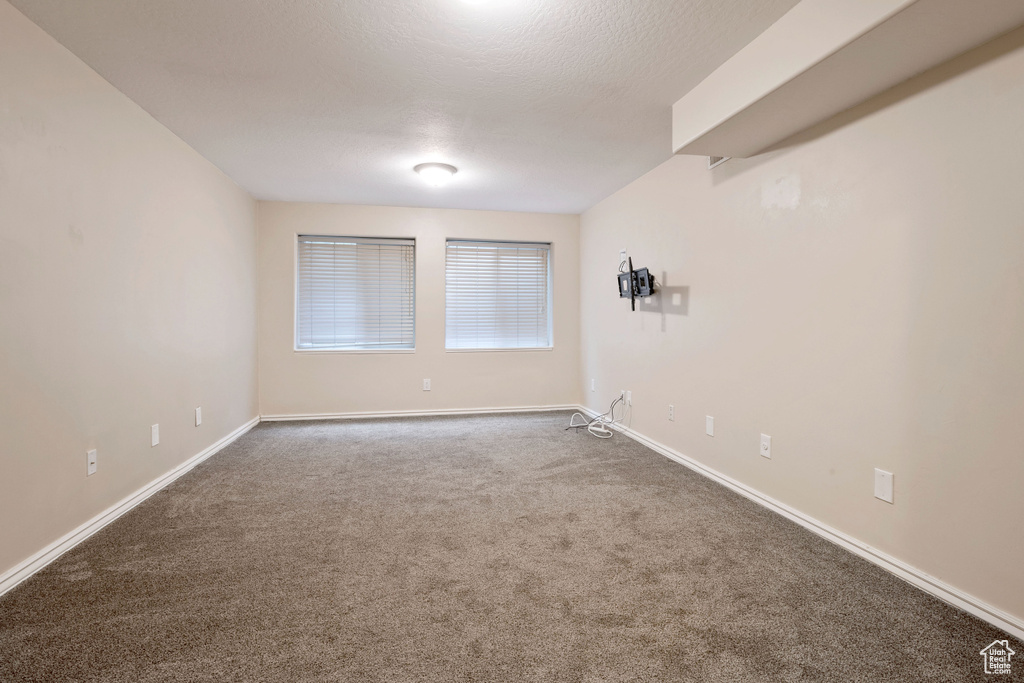 Carpeted spare room featuring baseboards