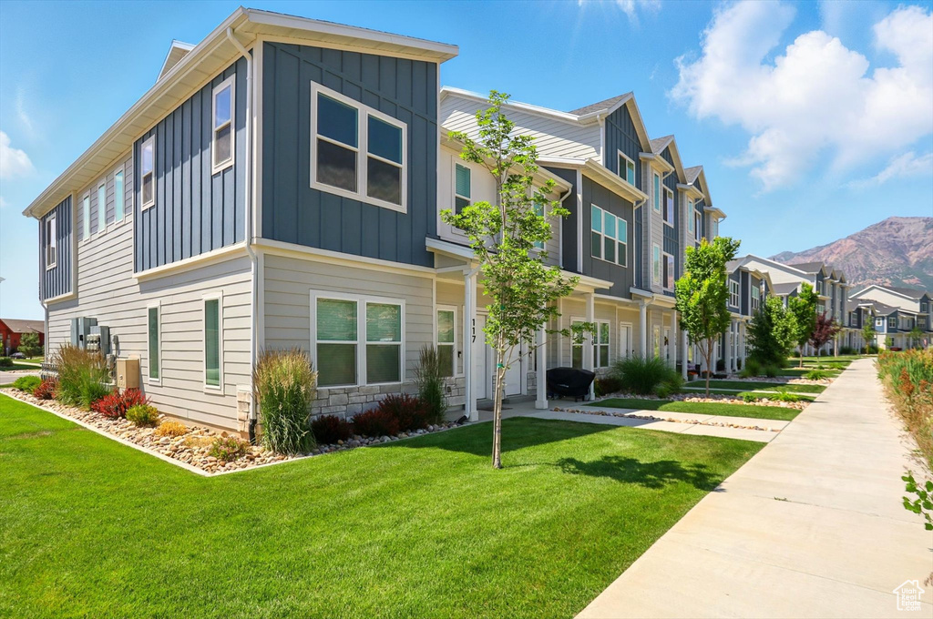 View of front of property featuring board and batten siding, a residential view, a front yard, and a mountain view