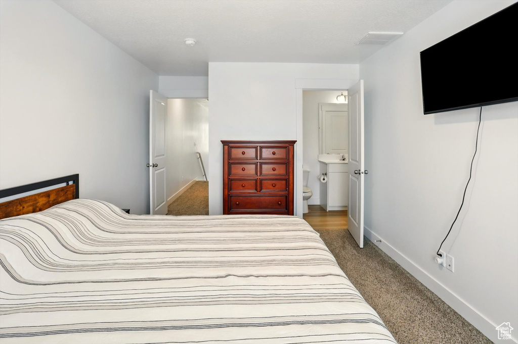 Carpeted bedroom with baseboards and ensuite bathroom