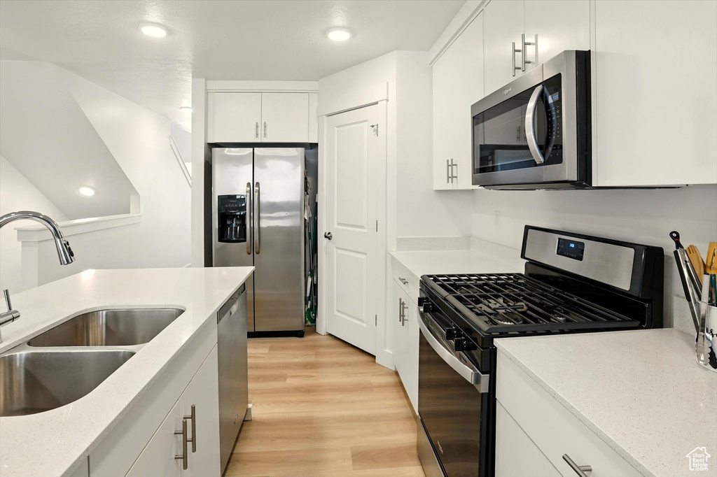 Kitchen featuring appliances with stainless steel finishes, light wood-type flooring, white cabinetry, and recessed lighting