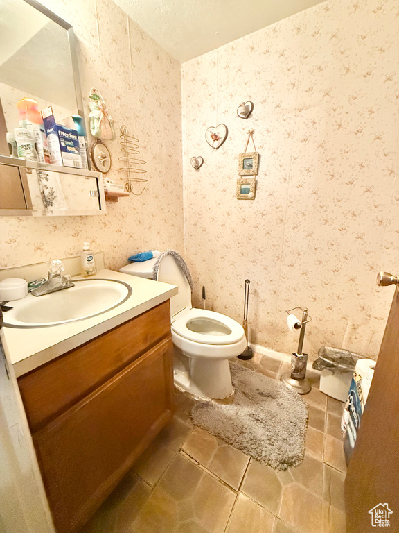 Half bathroom featuring vanity, wallpapered walls, and tile patterned floors