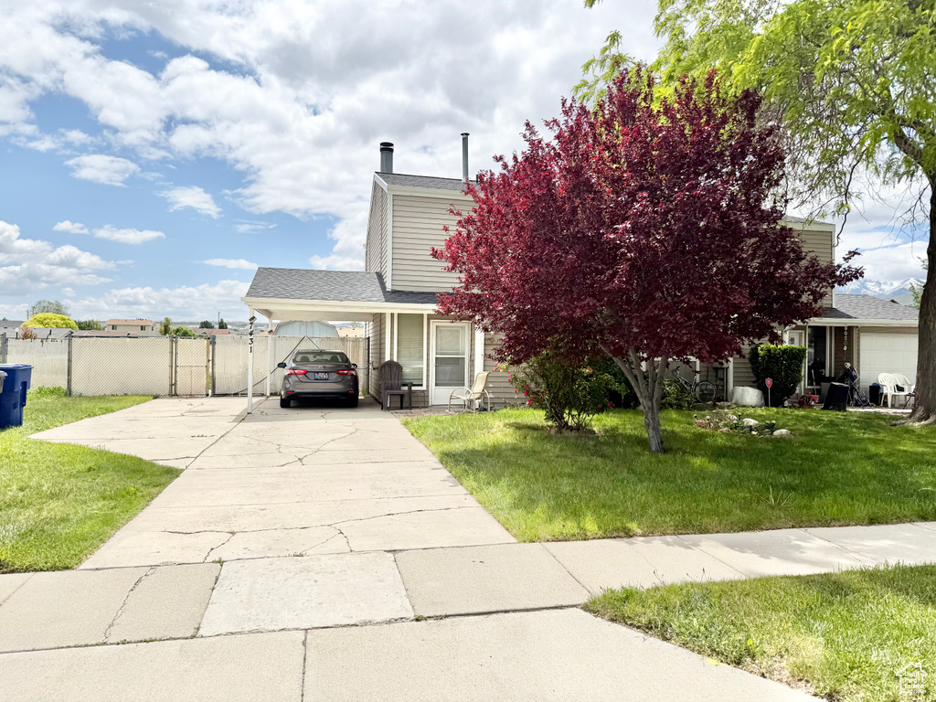 View of property hidden behind natural elements with concrete driveway and an attached carport