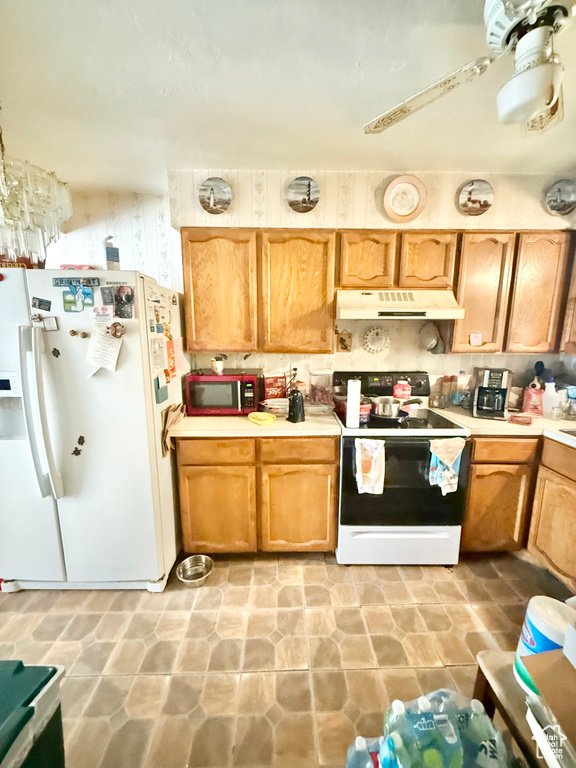 Kitchen with white appliances, under cabinet range hood, and light countertops