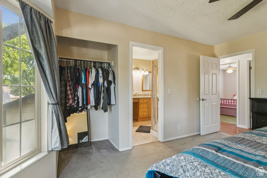 Bedroom with a closet, carpet flooring, ensuite bathroom, a walk in closet, and a textured ceiling
