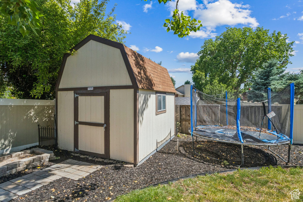 View of shed featuring a trampoline and a fenced backyard