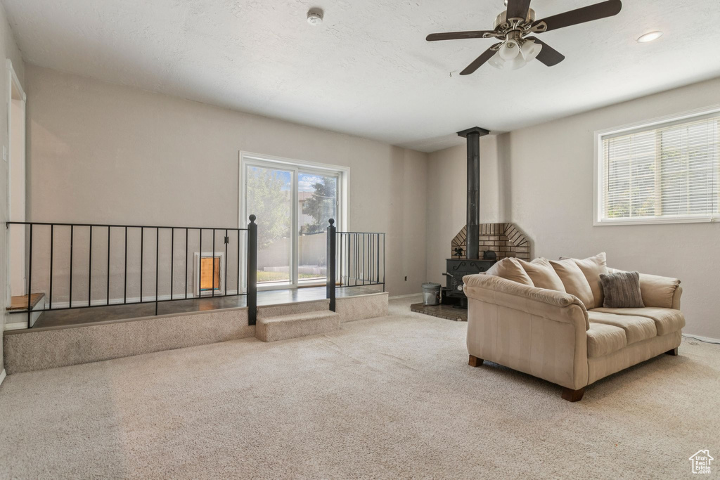 Carpeted living area with a wood stove, ceiling fan, and recessed lighting
