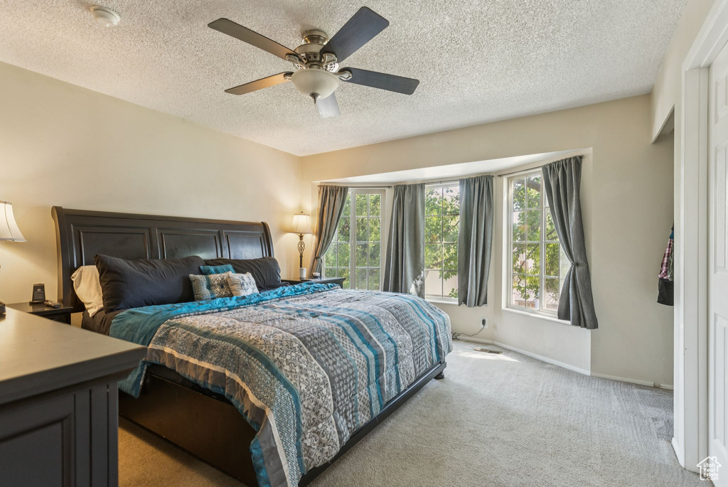 Bedroom with carpet, a textured ceiling, and a ceiling fan