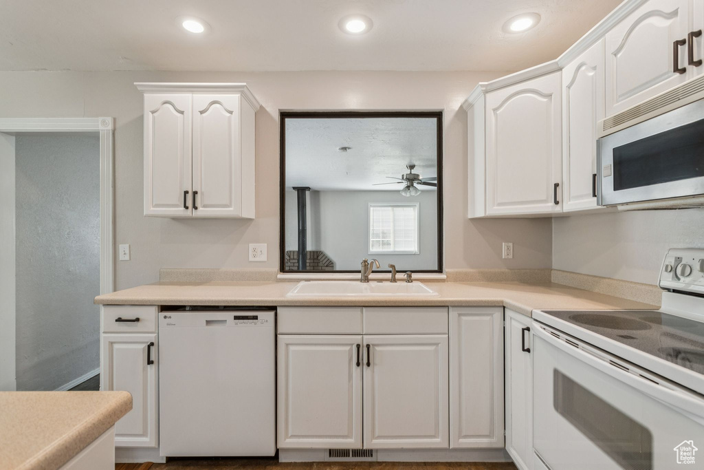 Kitchen with white appliances, white cabinets, ceiling fan, light countertops, and recessed lighting