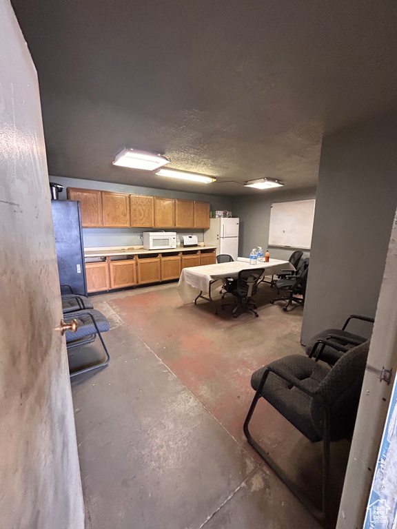 Interior space with white appliances, concrete flooring, and brown cabinetry