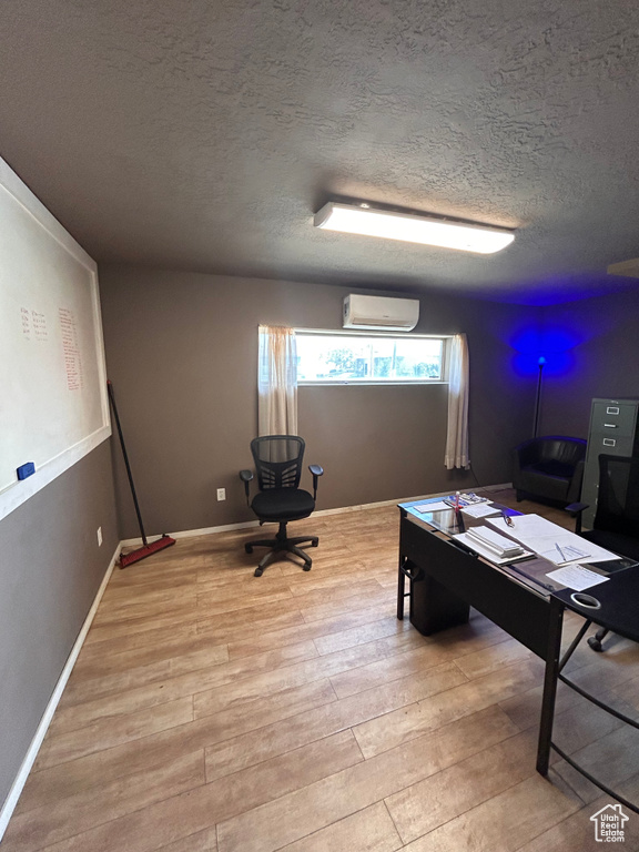 Office space with a wall mounted AC, a textured ceiling, and wood finished floors
