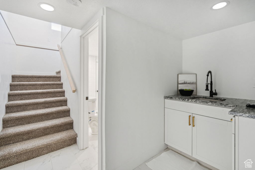 Bar area featuring light marble finish flooring, stairs, and recessed lighting