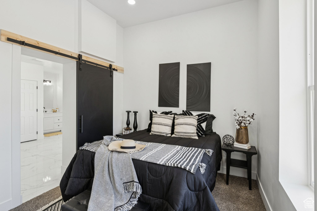 Bedroom with a barn door, ensuite bathroom, baseboards, recessed lighting, and marble finish flooring