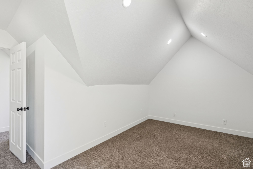 Bonus room featuring dark carpet, vaulted ceiling, baseboards, and recessed lighting