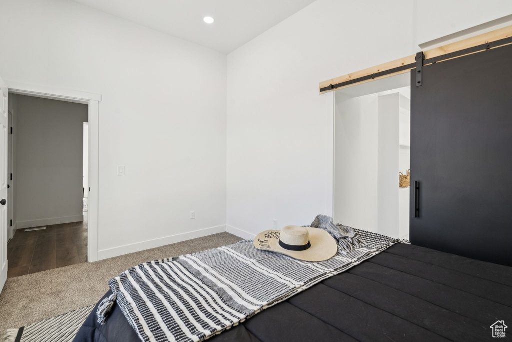 Carpeted bedroom with a barn door, baseboards, and recessed lighting