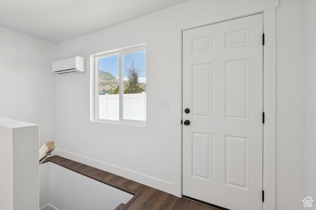 Entryway featuring an AC wall unit, baseboards, and dark wood-style flooring