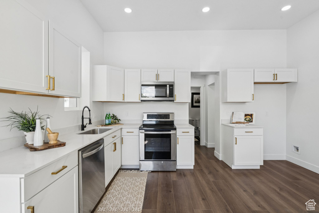 Kitchen featuring appliances with stainless steel finishes, a sink, dark wood-style floors, white cabinets, and recessed lighting