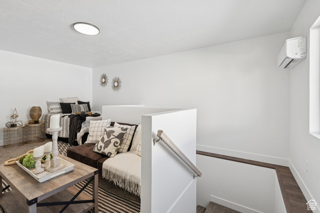 Living room with an AC wall unit, wood finished floors, and baseboards