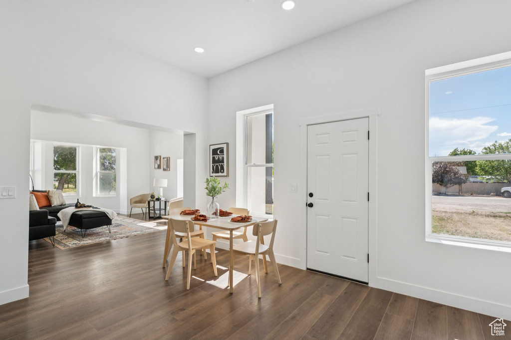 Dining room featuring dark wood finished floors, recessed lighting, baseboards, and a high ceiling