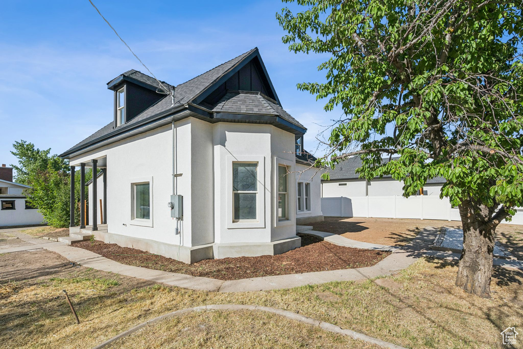 View of side of home with stucco siding and a shingled roof