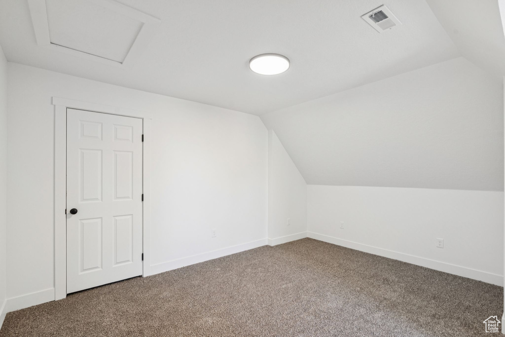 Bonus room with vaulted ceiling, carpet, baseboards, and attic access