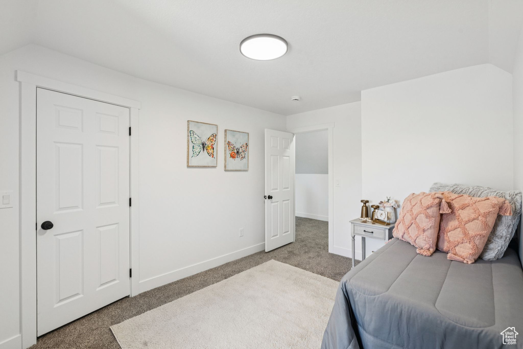 Carpeted bedroom featuring baseboards and vaulted ceiling