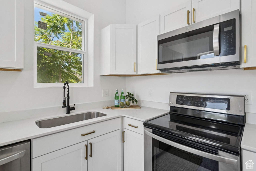 Kitchen with appliances with stainless steel finishes, a sink, plenty of natural light, and light countertops