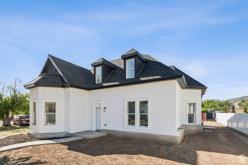 Rear view of house with stucco siding and roof with shingles