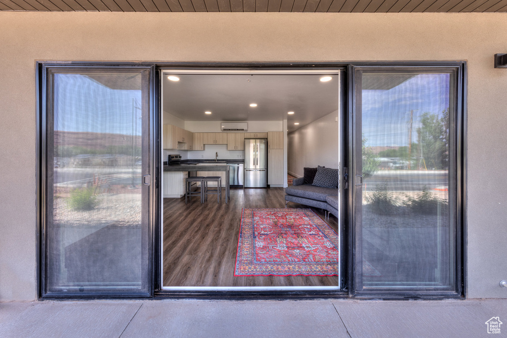 Property entrance with stucco siding and a wall unit AC