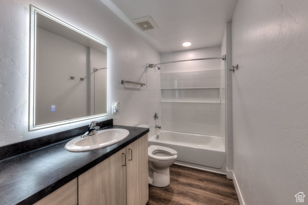 Full bathroom featuring wood finished floors, vanity, and  shower combination