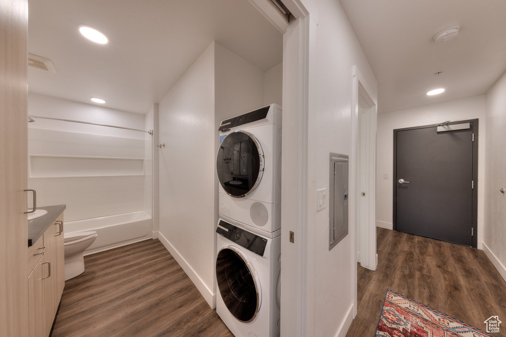 Laundry area with stacked washer / dryer, dark wood finished floors, recessed lighting, and electric panel