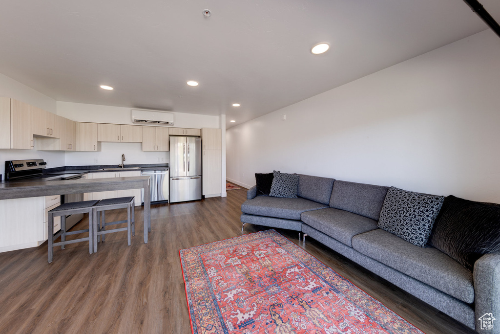 Living room with a wall mounted air conditioner, dark wood-type flooring, and recessed lighting