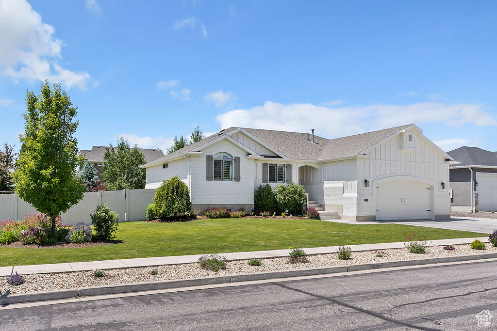 Ranch-style home with an attached garage, board and batten siding, concrete driveway, and a shingled roof