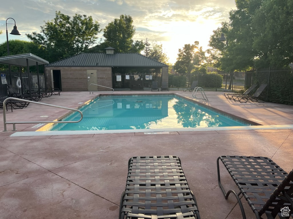 Pool at dusk with a patio and a community pool