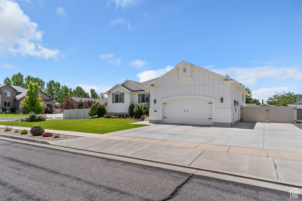Ranch-style home with an attached garage, a gate, driveway, and board and batten siding