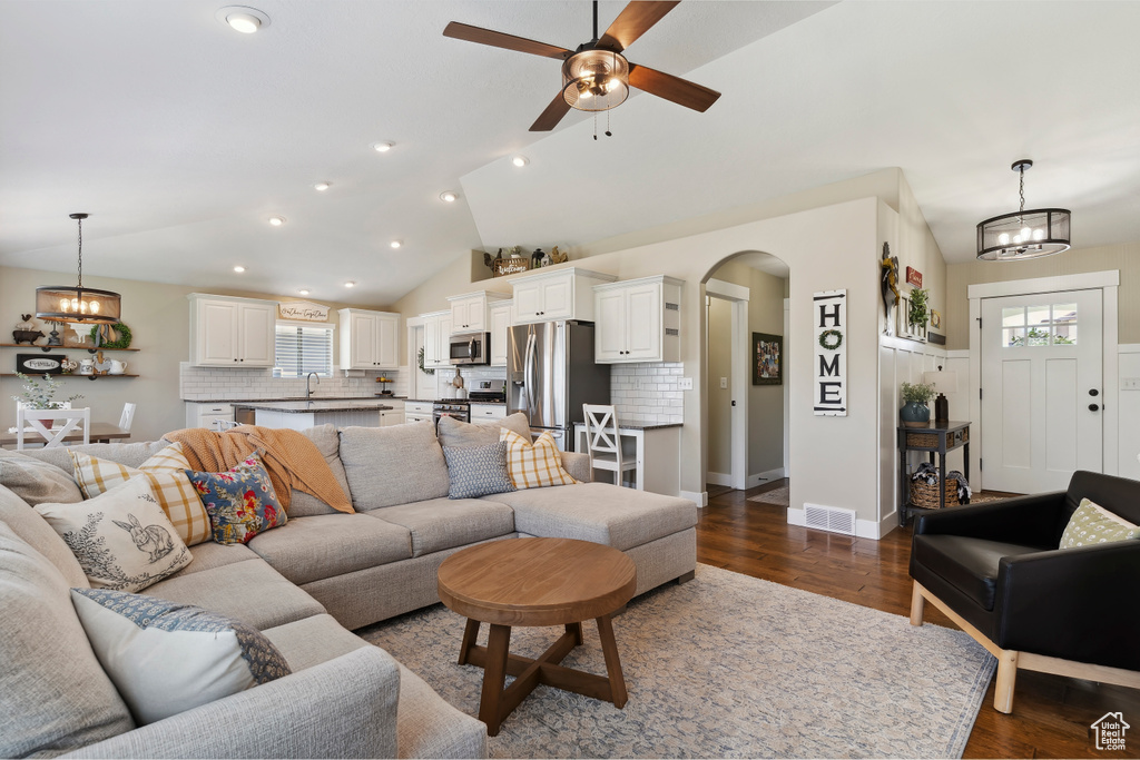 Living area featuring arched walkways, dark wood-style floors, a chandelier, ceiling fan, and recessed lighting