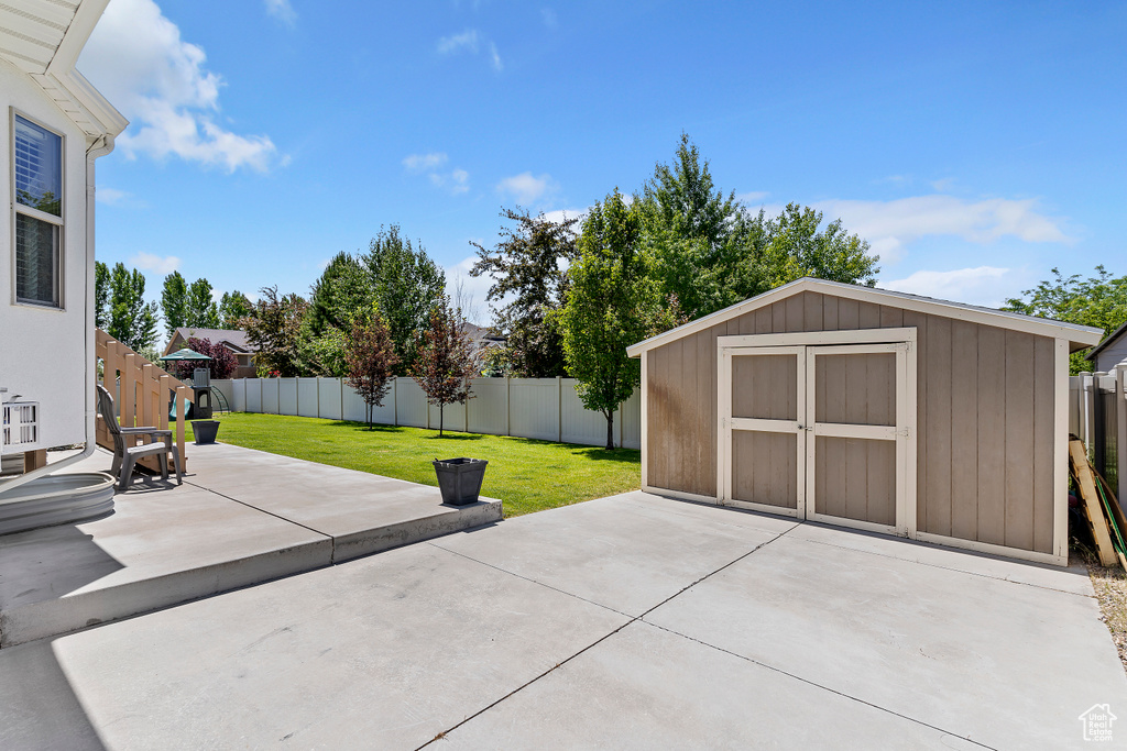 Fenced backyard with a patio area and a storage unit