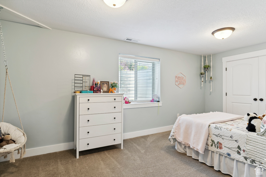 Bedroom featuring carpet floors, a textured ceiling, and a closet