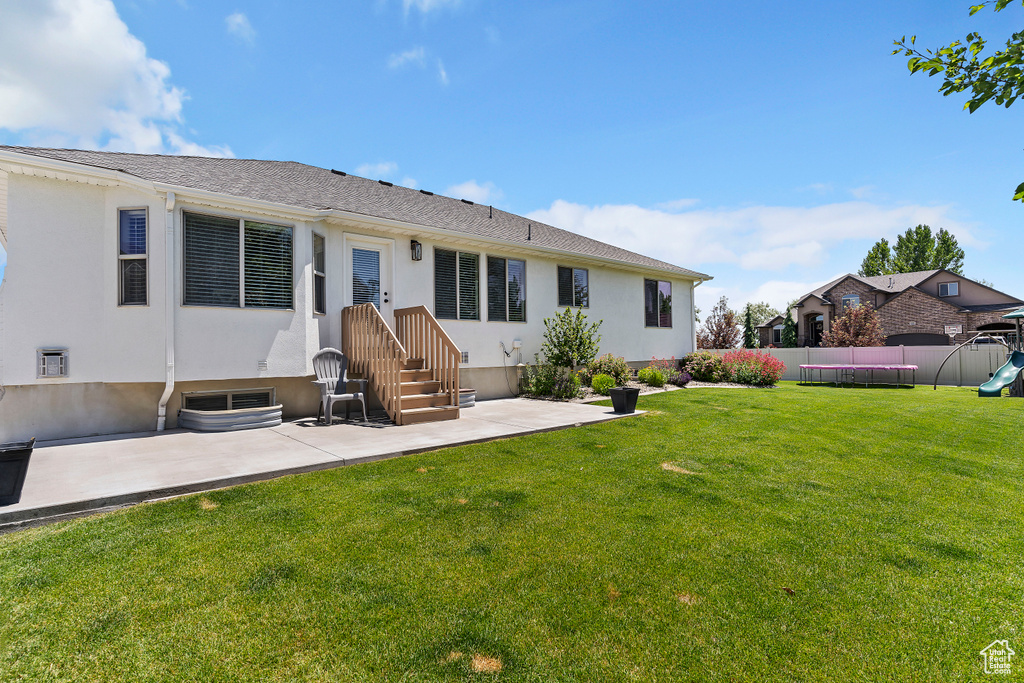 Rear view of house with a patio area, stucco siding, and a playground