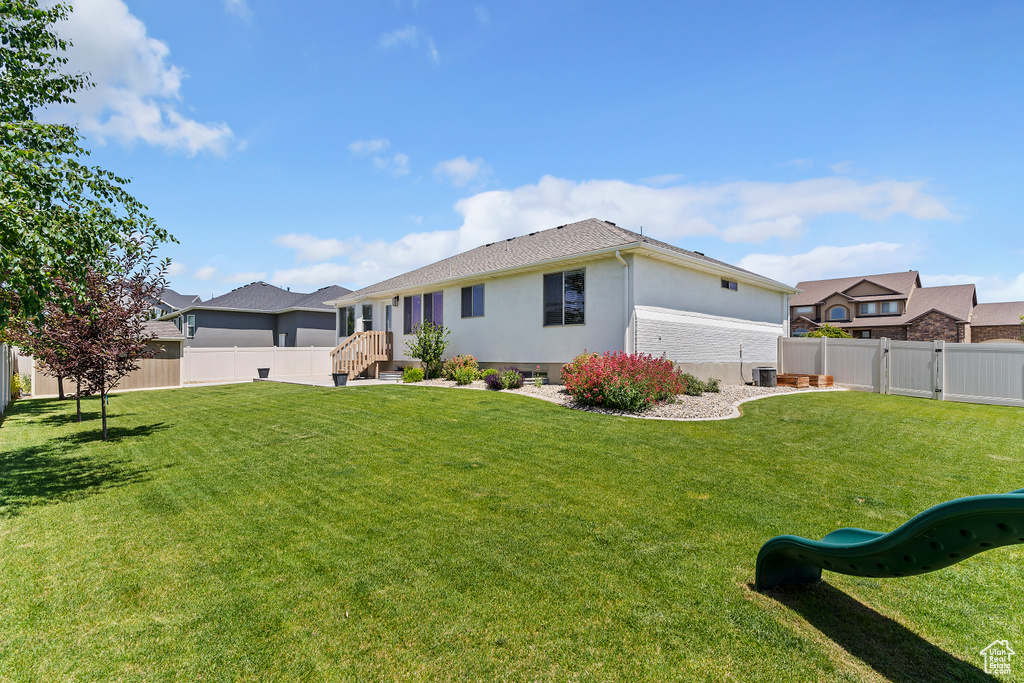 Rear view of house featuring a fenced backyard, a playground, and stucco siding