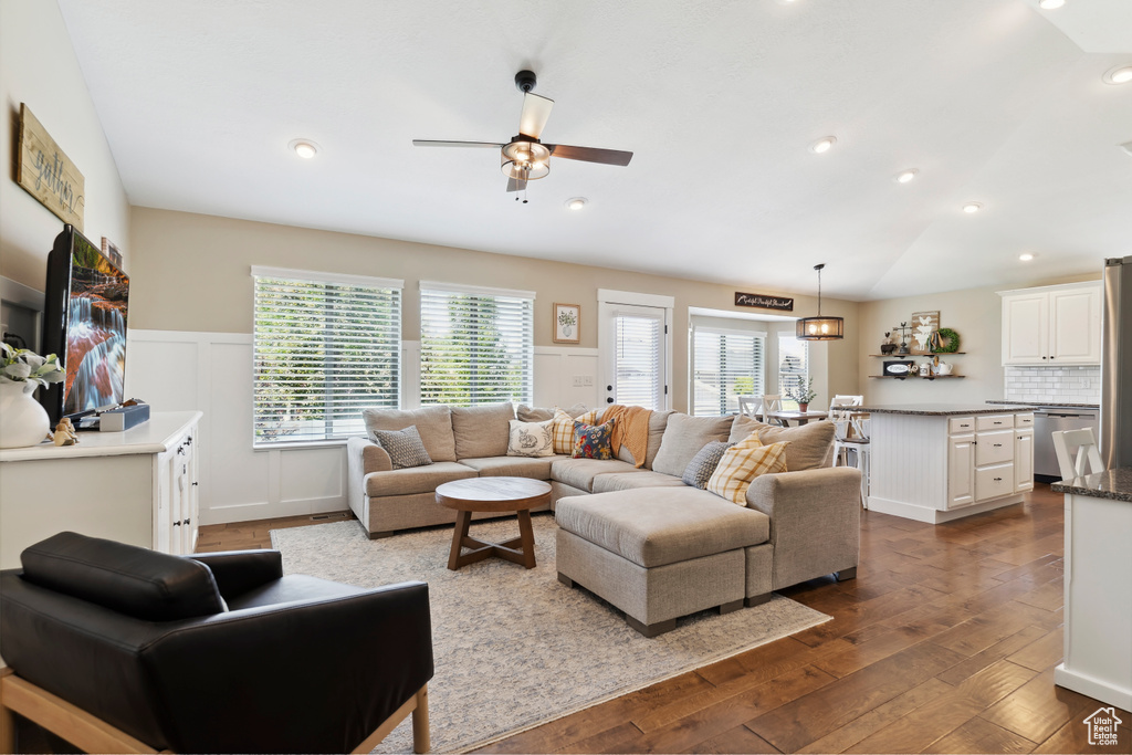 Living area with a ceiling fan, dark wood finished floors, a wainscoted wall, recessed lighting, and a decorative wall
