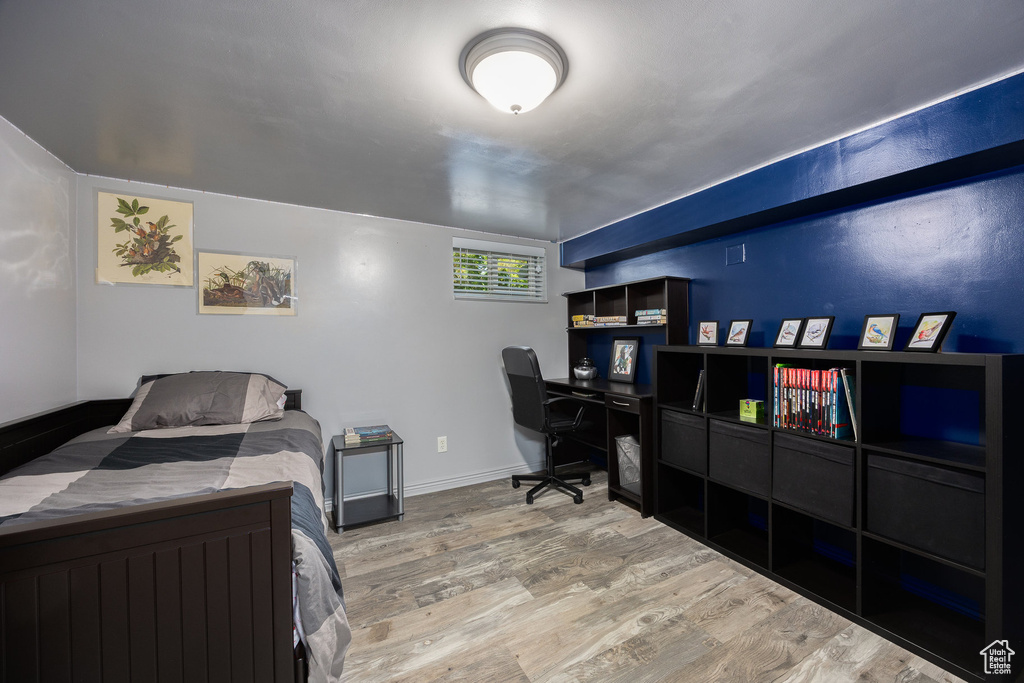 Bedroom with wood finished floors and an office area