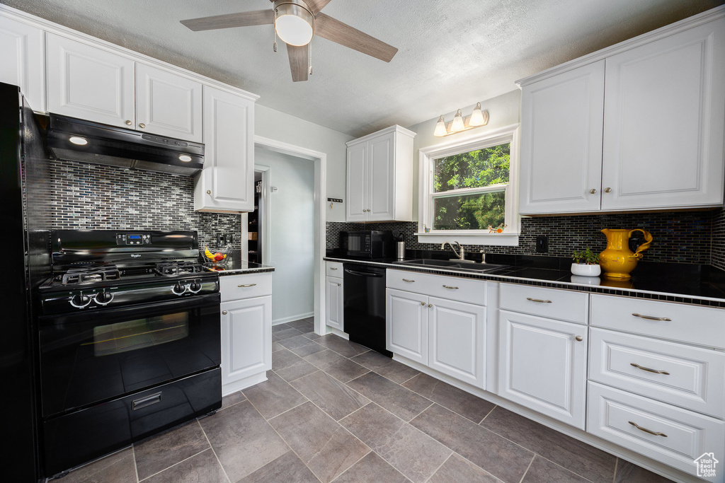Kitchen with black appliances, under cabinet range hood, dark countertops, ceiling fan, and tasteful backsplash