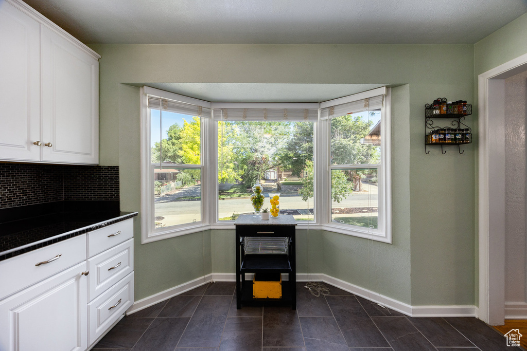 Kitchen with dark countertops, healthy amount of natural light, and white cabinetry