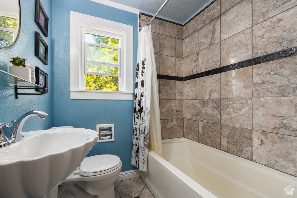 Bathroom with shower / tub combo with curtain and tile patterned flooring