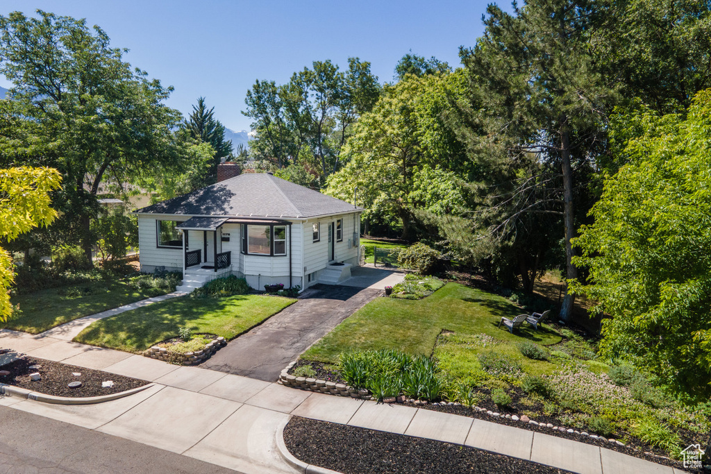 Bungalow-style home with a chimney, a front yard, and asphalt driveway