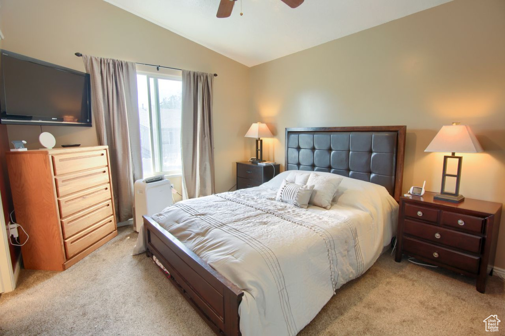 Bedroom featuring light colored carpet, vaulted ceiling, and a ceiling fan