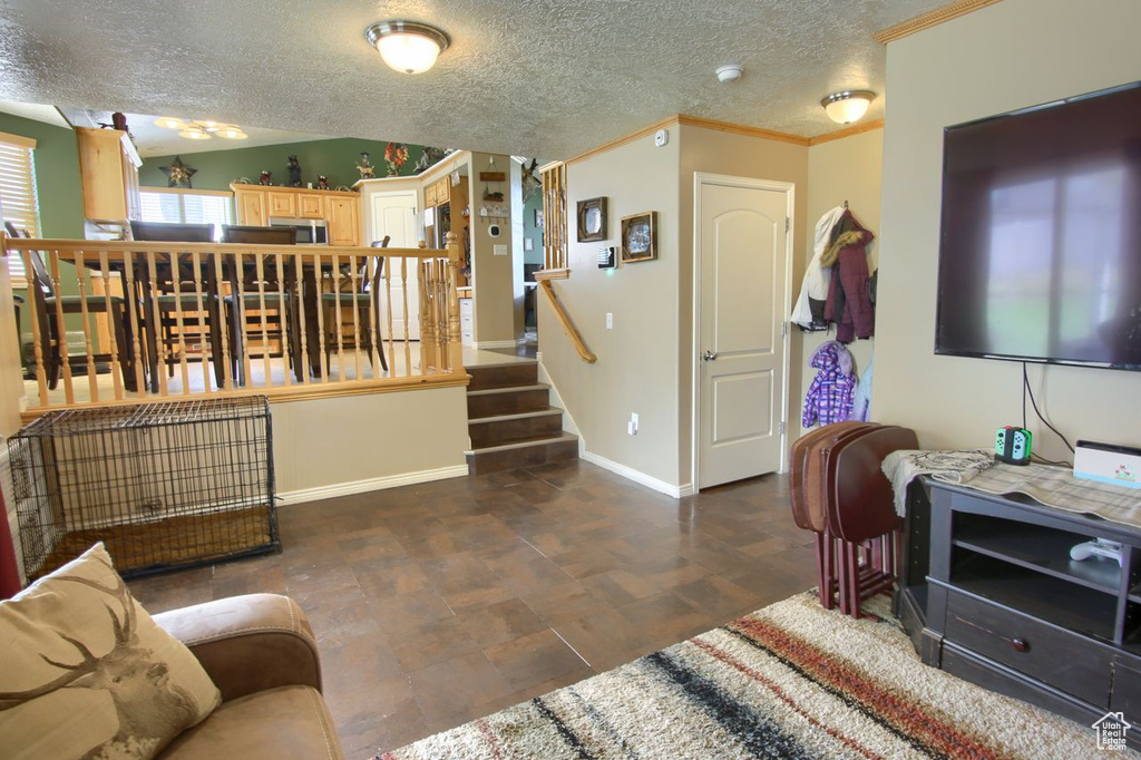 Living area with crown molding, a textured ceiling, and stairs