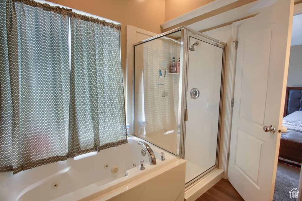 Bathroom featuring a shower stall, a jetted tub, and connected bathroom