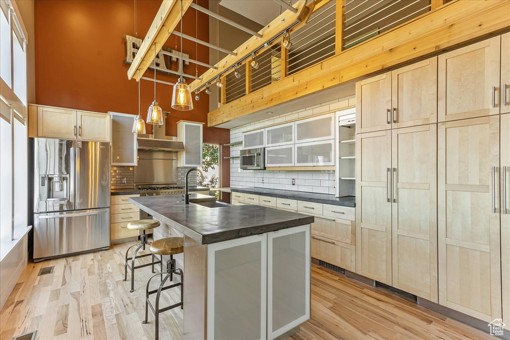 Kitchen with appliances with stainless steel finishes, a sink, dark countertops, a high ceiling, and backsplash