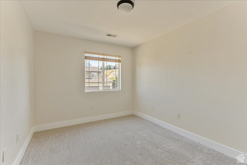 Empty room with light colored carpet and baseboards